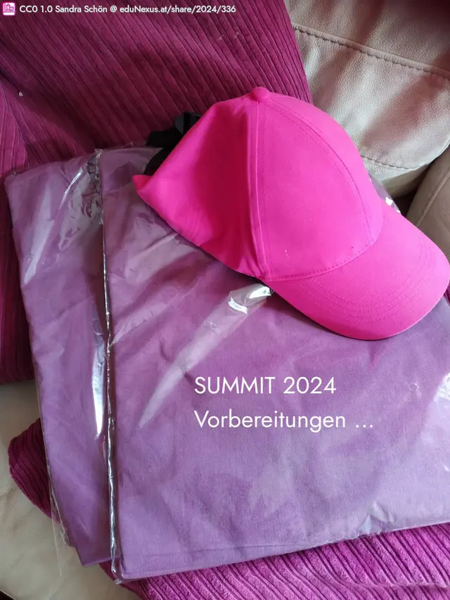 Pinke Kappe auf verpackter Kleidung, mit dem Text „SUMMIT 2024 Vorbereitungen …“.