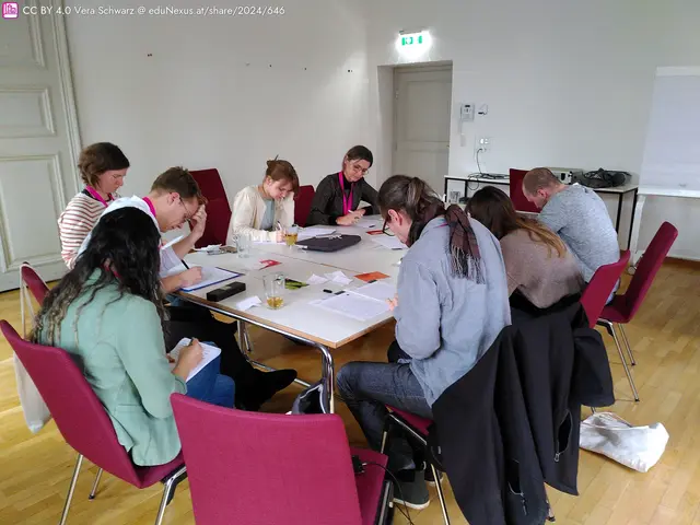 Eine Gruppe von acht Personen sitzt um einen Tisch, alle sind mit Notizen beschäftigt. Einige haben Stifte in der Hand, auf dem Tisch liegen verschiedene Unterlagen und Getränke. Die Umgebung ist hell und modern.