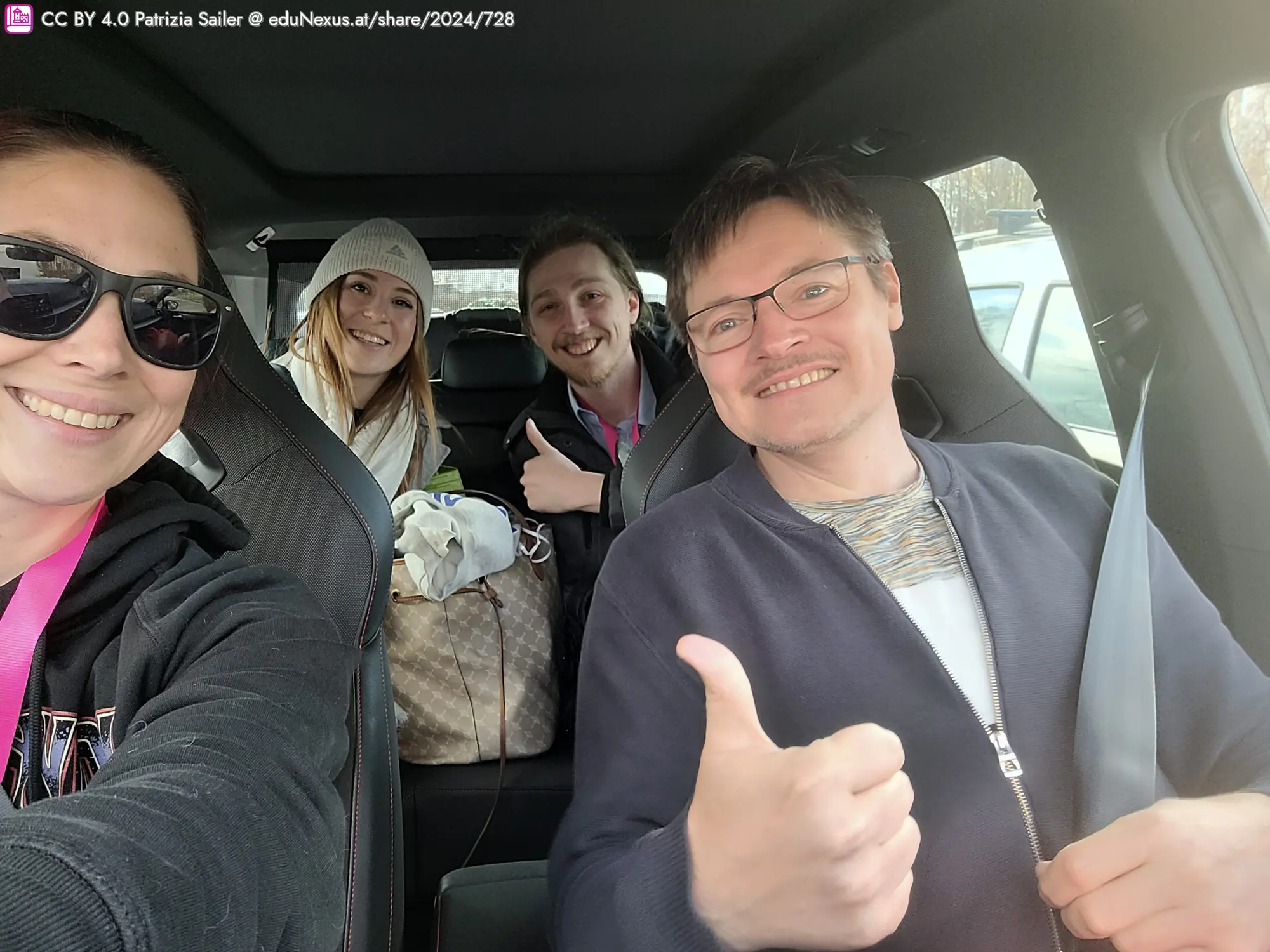 Vier Personen im Auto, lächelnd und posierend für ein Selfie.